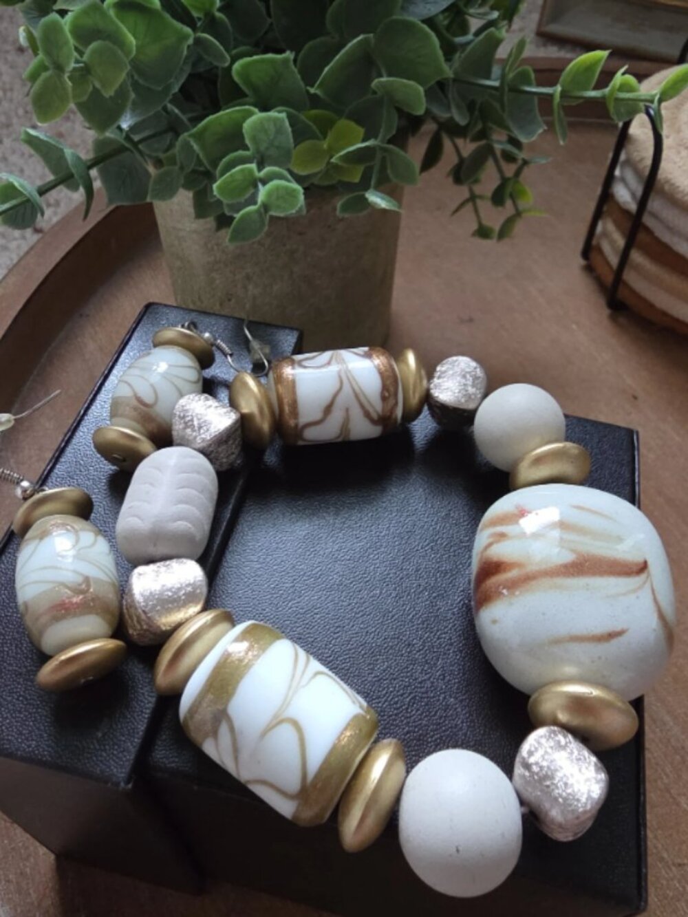 set of handcrafted jewelry featuring large, artisanal white and gold beads